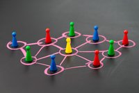 Verschiedenfarbige Spielfiguren stehen in Kreidekreisen, die mit Strichen verbunden sind.