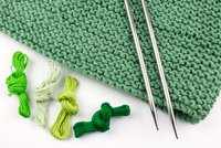 Garne und Strickstoff in Grüntönen und Stricknadeln
