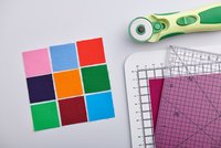 Hhelle quadratische Stoffstücke und Steppzubehör