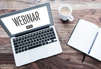 Vogelperspektive Blick auf Laptop-Computer am Schreibtisch mit Wort Webinar am Computer-Bildschirm angezeigt.